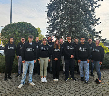 Ausbildungsstart bei Hosta: Mehrere junge Hosta Mitarbeitende in einheitlichen Pullovern stehen auf einem Parkplatz.