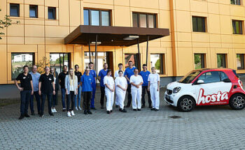Einige Hosta Mitarbeitende stehen beisammen, daneben ein kleines Auto mit dem Hosta Logo.